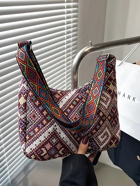 Embroidered geometric hobo bag with colorful strap.