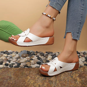 White slip-on wedge sandals with riveted detail and cut-out design.