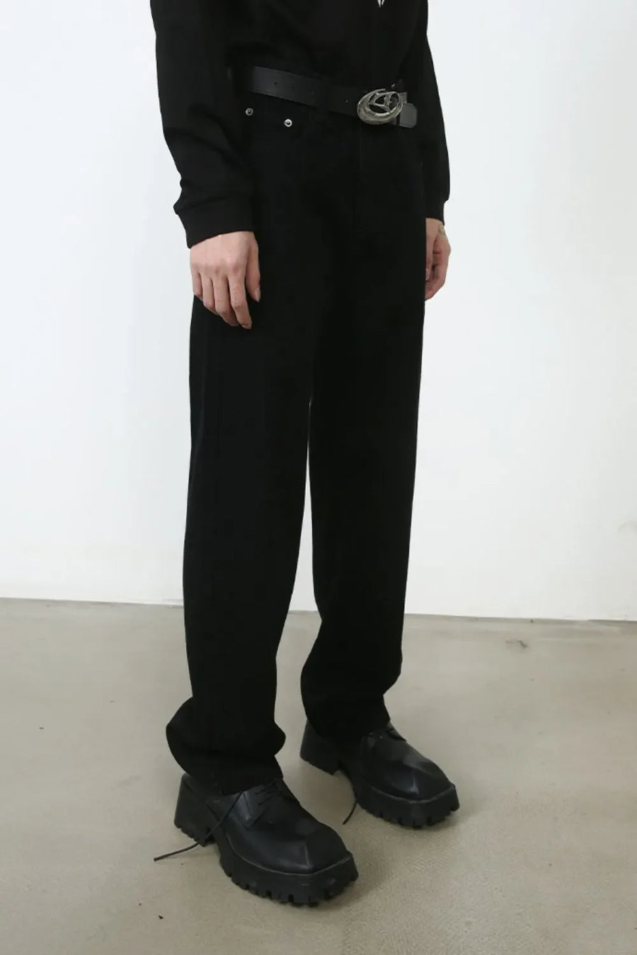 Relaxed fit black denim trousers with a silver buckle belt and chunky shoes.