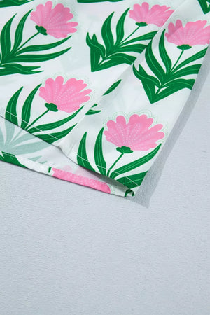White polyester blouse with pink floral and green leaf print, showing hem detail.