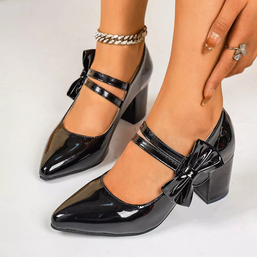 Black patent pointed toe block heel pumps with double ankle straps and bow detail.