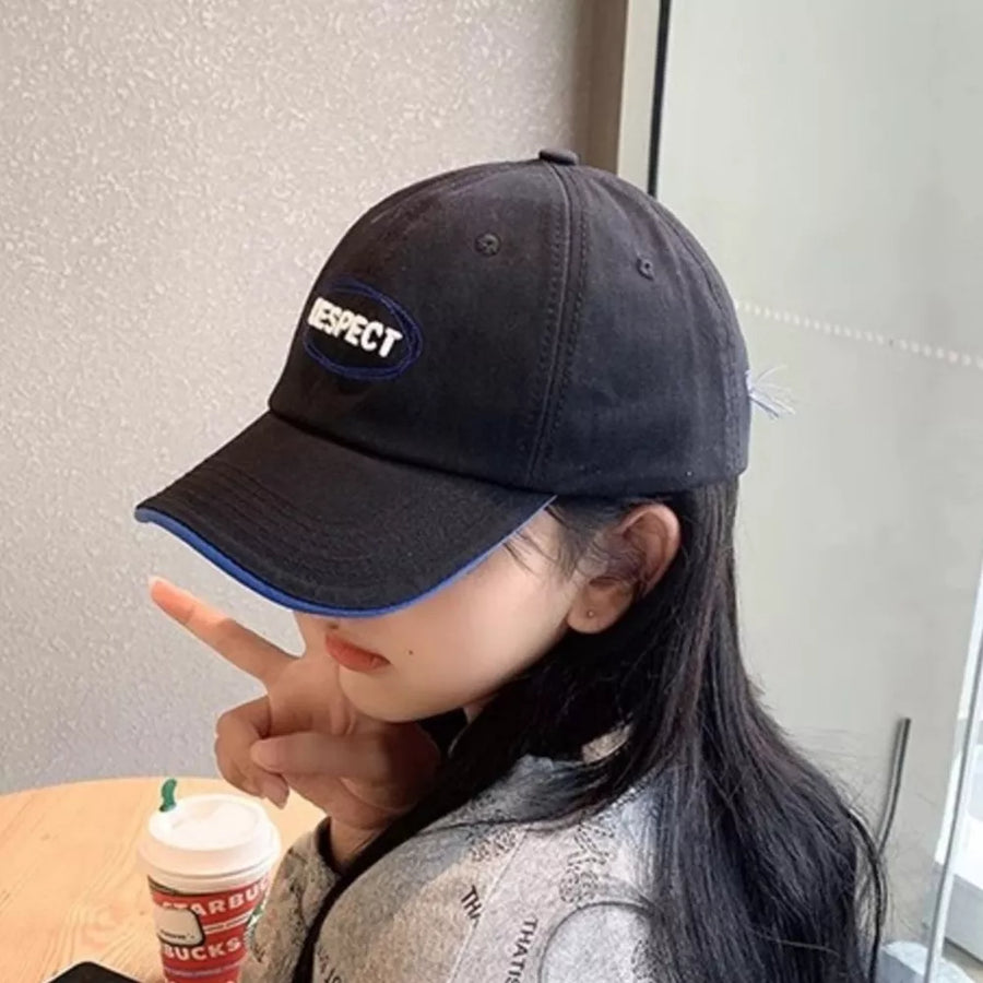 Black baseball cap with embroidered oval "RESPECT" detail and blue brim trim.