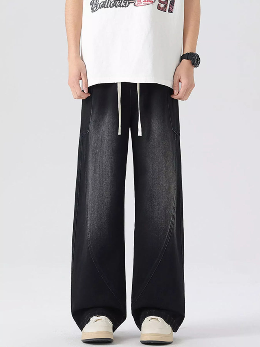 Oversized wide-leg jeans in black denim with drawstring waist and vintage wash.