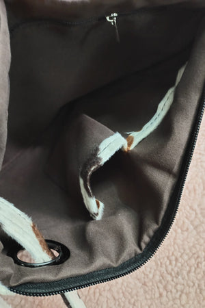 Brown/cream cowhide print clutch bag interior with zipper and wristlet strap detail.