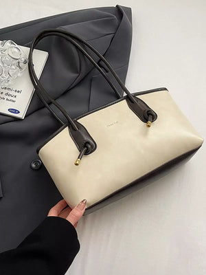 Beige leather shoulder bag with dark brown trim and handles, gold hardware detail