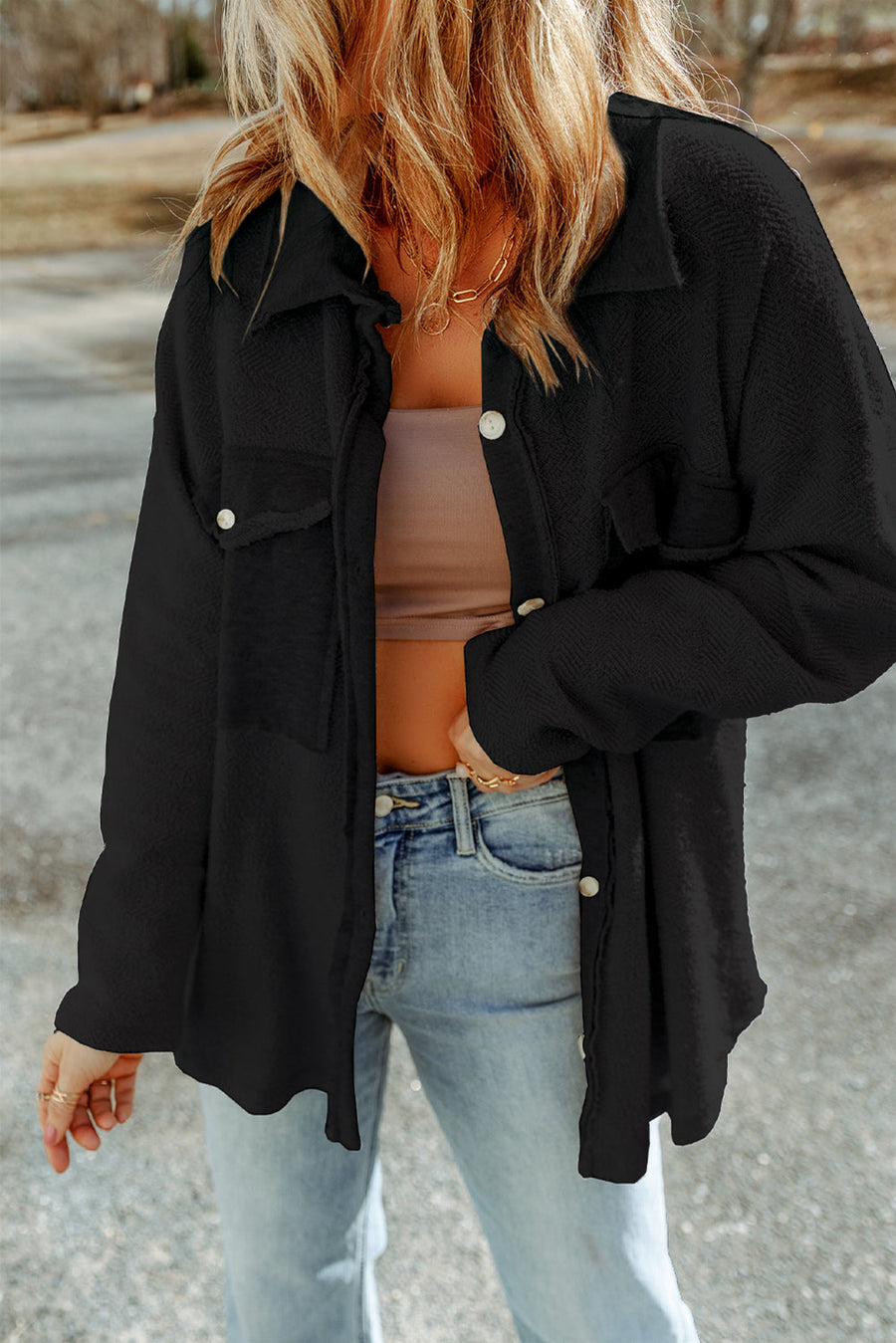 Black button-up coat with textured fabric and chest pockets.