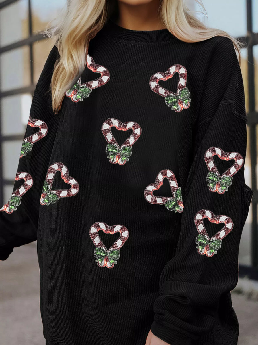 Black crewneck sweatshirt with all-over sequin candy cane heart pattern and green bows.
