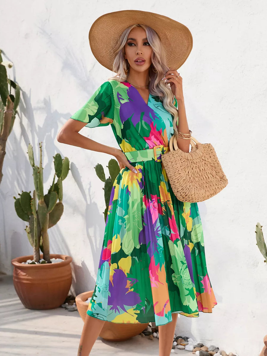 Tropical pleated midi dress in dark green with a vibrant floral print and matching belt.