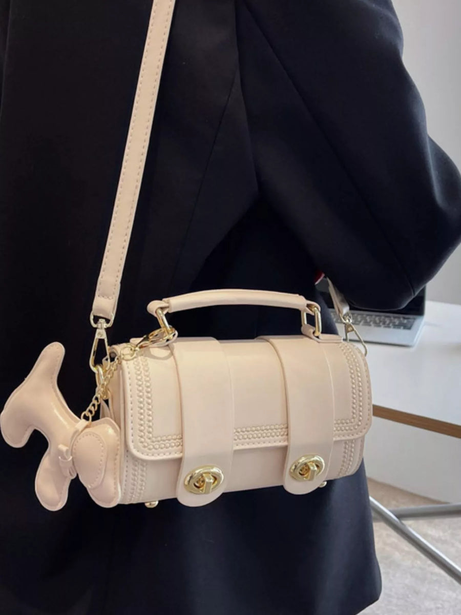 Mini crossbody bag in beige PU leather with dog charm and gold hardware.