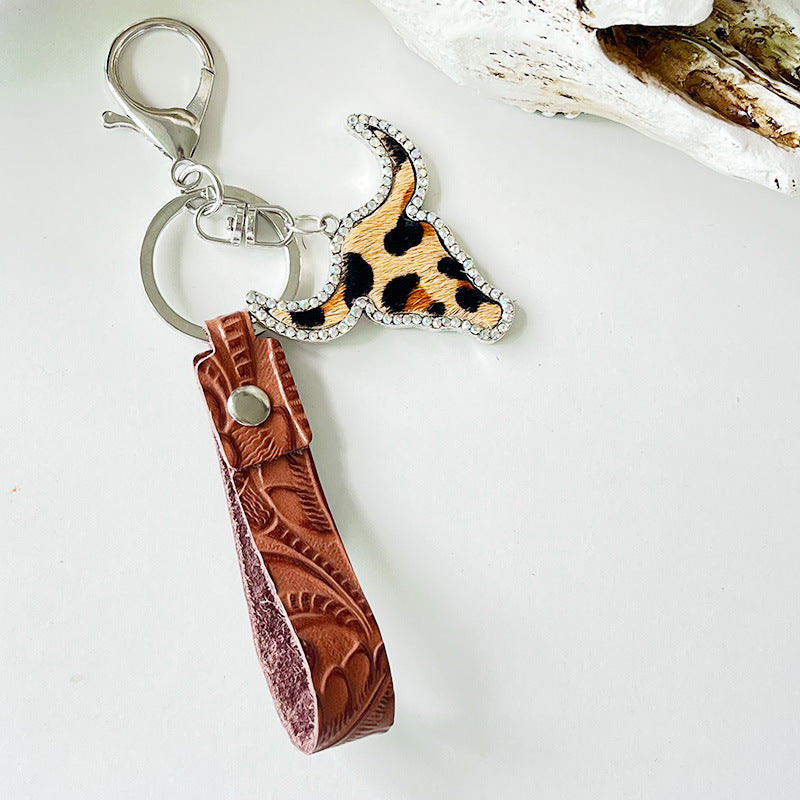 Western keychain with leopard print bull skull, crystals, and tooled leather strap.
