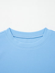 Light blue textured blouse with crew neck and bubble sleeves