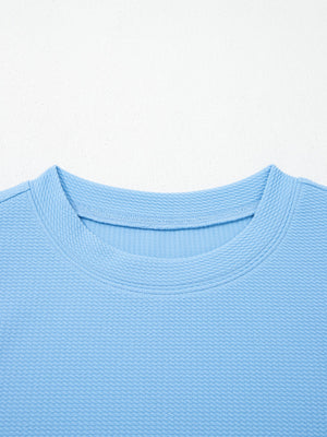 Light blue textured blouse with crew neck and bubble sleeves