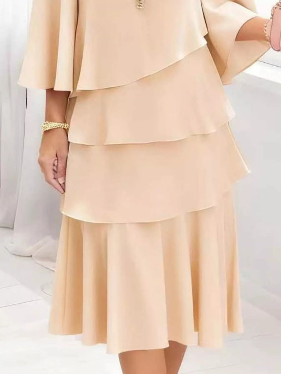 Elegant tiered dress in blush pink with 3/4 sleeves and a ruffled hem.
