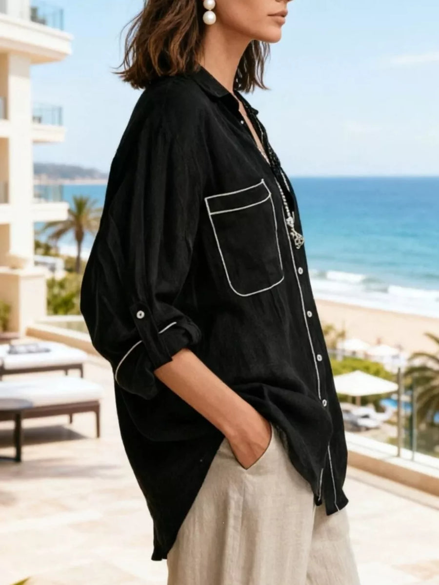 Black linen shirt with white piping, button front, chest pockets and rolled sleeves.