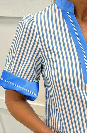 Vibrant striped shirt with blue color block detail and decorative stitching.
