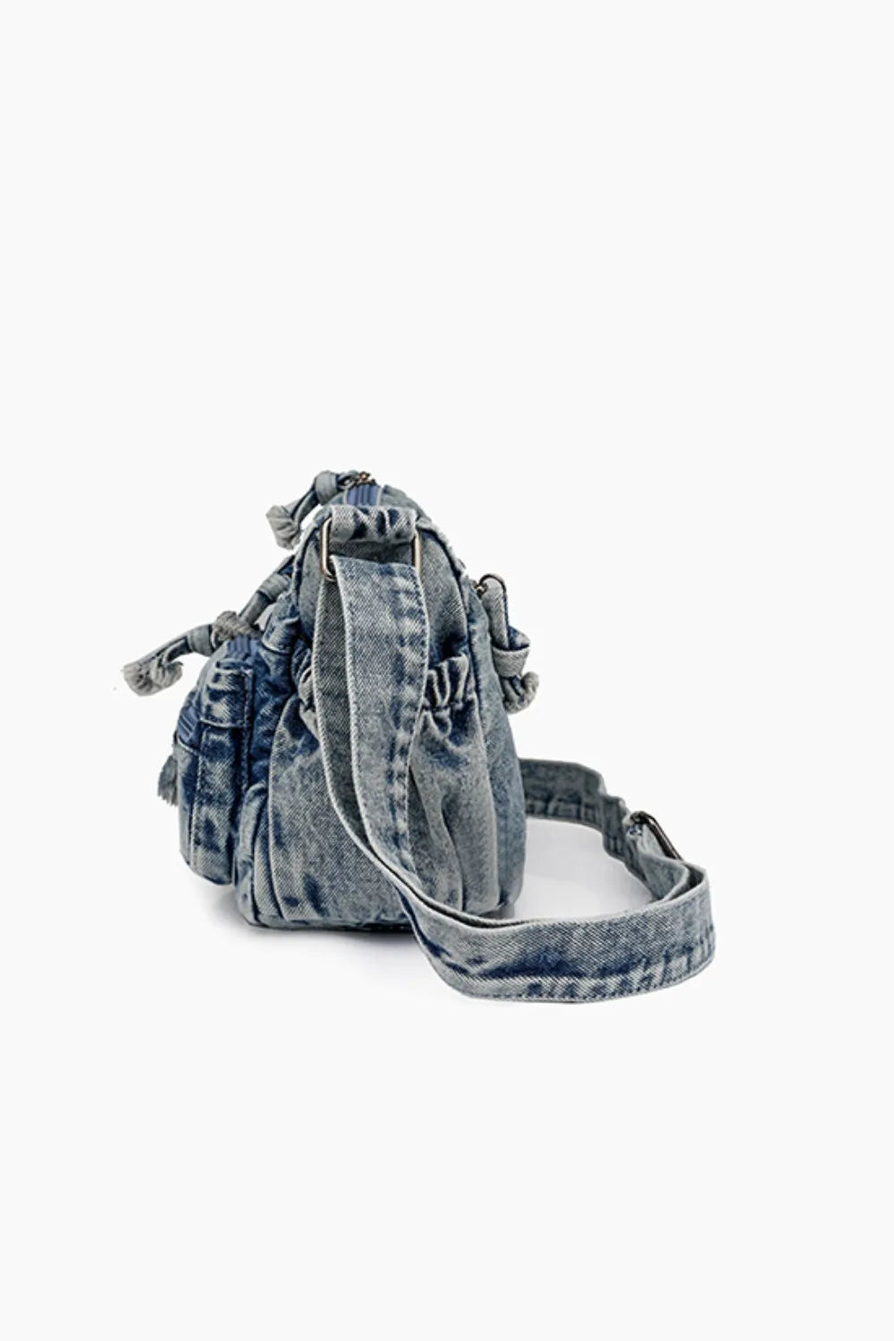 Acid wash denim crossbody bag with drawstring closure and adjustable strap.