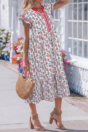 Vibrant floral tiered midi dress with V-neck, short sleeves, and red stripe detail.