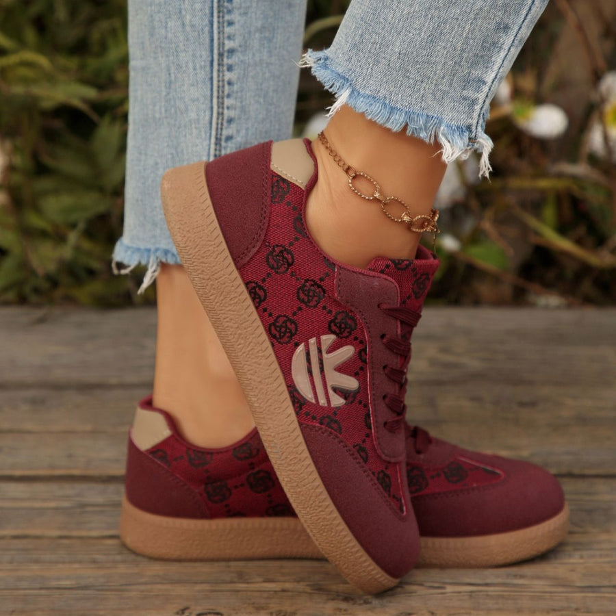 Red lace up sneakers with all over pattern and tan sole.