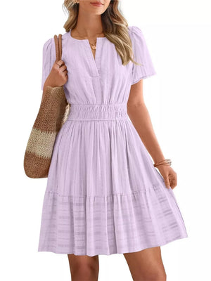 Textured V-neck tiered dress in light purple with smocked waist and short sleeves.