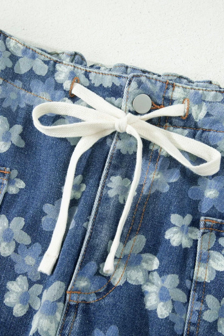 Blue floral denim barrel jeans with white drawstring and pockets.