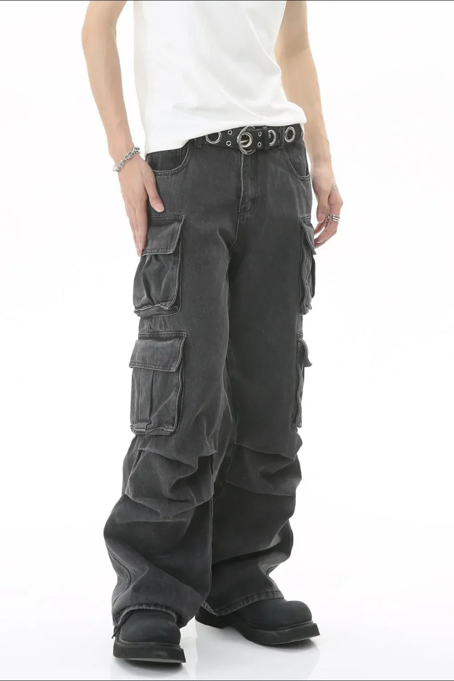 Baggy dark wash denim cargo pants with multiple pleated pockets and a silver grommet belt.