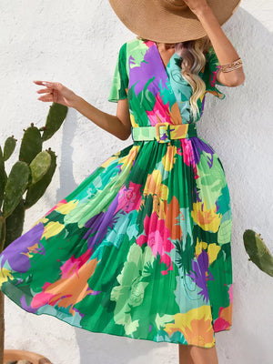 Green floral pleated midi dress with v-neck, short sleeves, and matching belt.