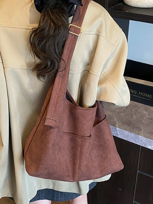 Large brown suede shoulder bag with adjustable strap and exterior pockets.