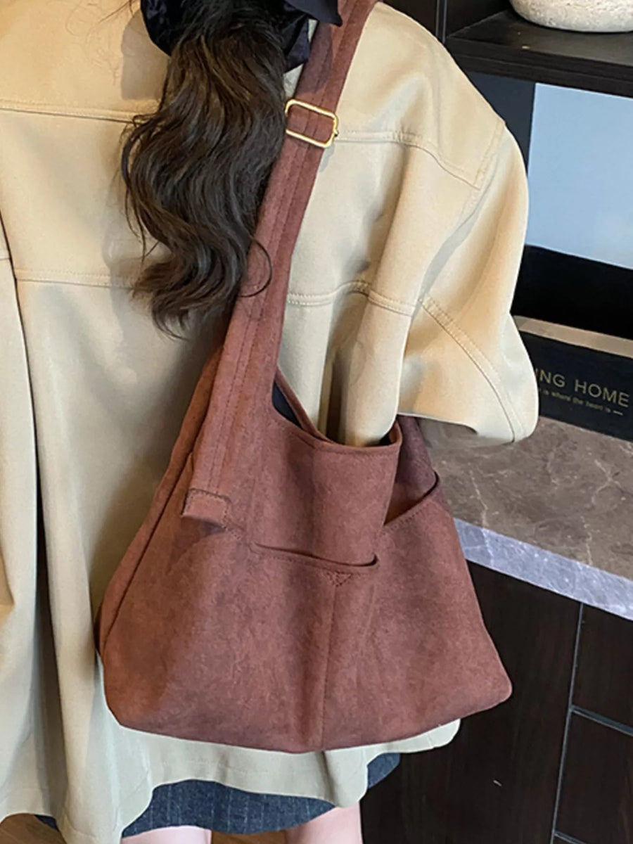 Large brown suede shoulder bag with adjustable strap and exterior pockets.