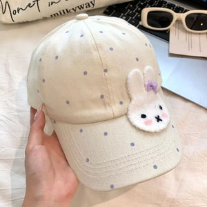 Ivory polka dot baseball cap with white bunny applique and purple bow.