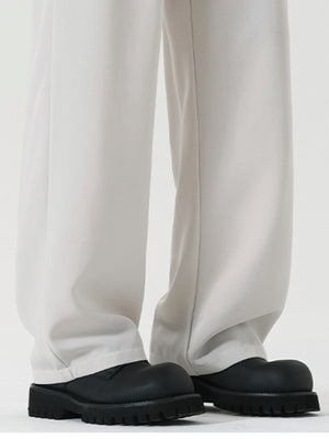 Men's white wide leg dress pants with a relaxed fit, styled with black chunky boots.