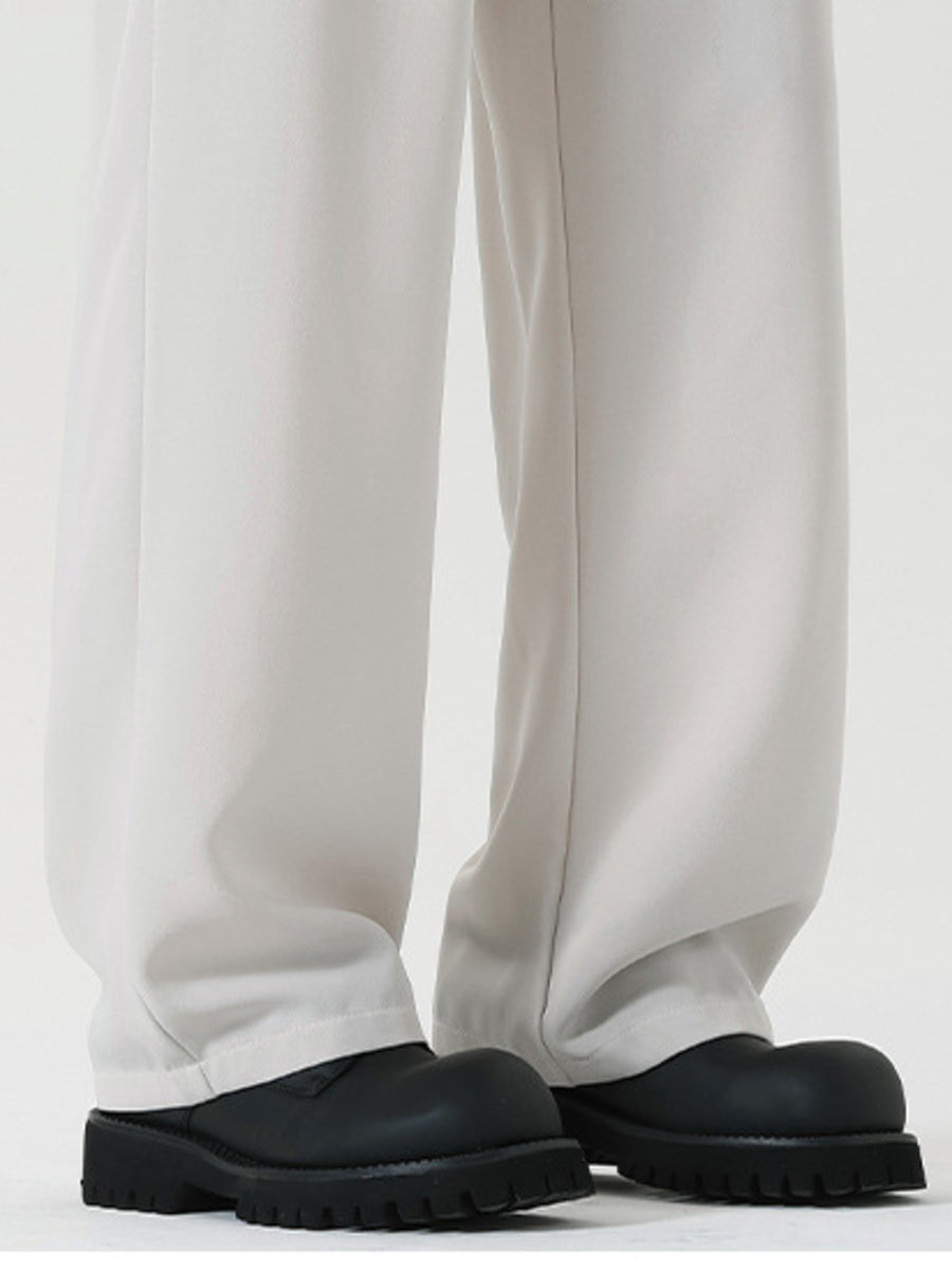 Men's white wide leg dress pants with a relaxed fit, styled with black chunky boots.