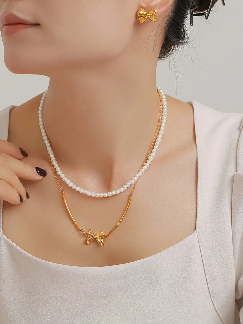 Gold bow and pearl layered necklace set with matching stud earrings.