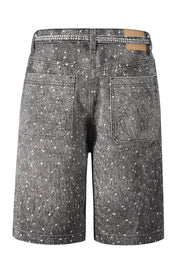 Embellished dark wash denim bermuda shorts with scattered white details and rhinestone waistband.