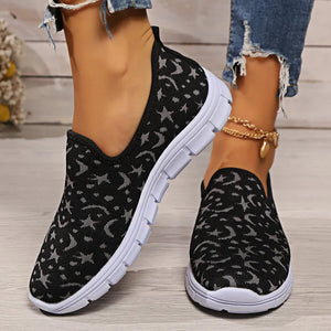 Black celestial knit slip-on sneakers with white soles and a moon and star pattern.