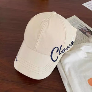 Cream baseball cap with navy blue embroidered "Cloud" text on the side and brim.