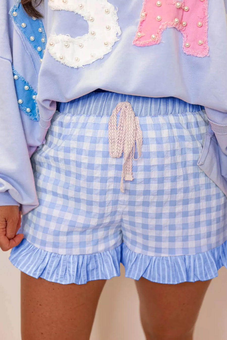 Light blue gingham cotton shorts with drawstring and ruffle hem