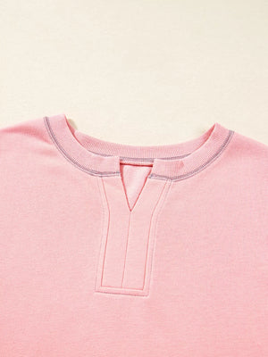 Dusty pink oversized sweatshirt with contrast stitching and a V-neck detail.