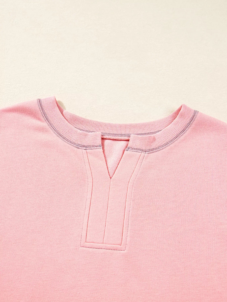 Dusty pink oversized sweatshirt with contrast stitching and a V-neck detail.