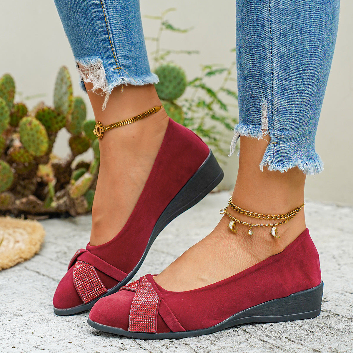 Red slip-on wedge flats with rhinestone-adorned bows and ankle straps.