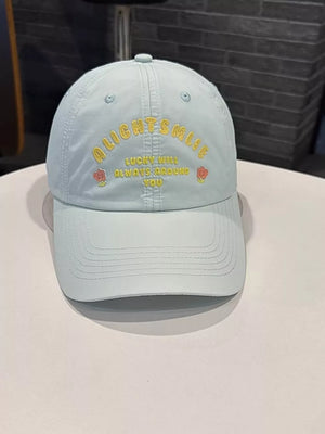 Light blue baseball cap with yellow embroidered text and rose details.