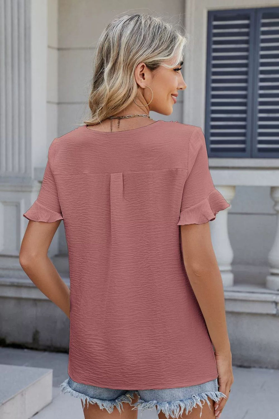 Dusty pink textured blouse with ruffle sleeves and a V-neckline.