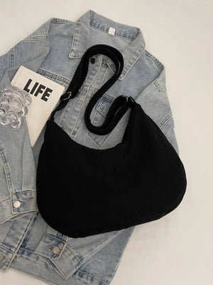 Black corduroy crescent shoulder bag with adjustable strap and silver hardware detail