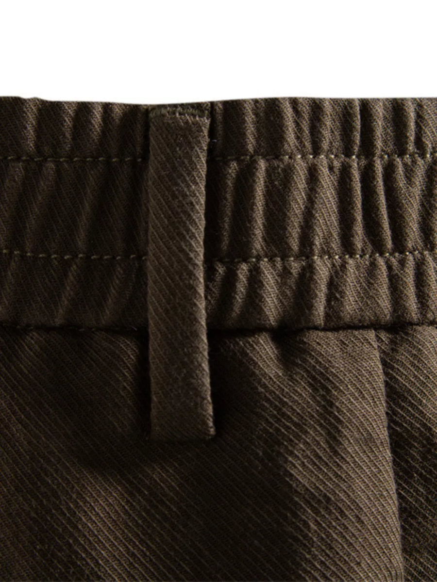 Classic pleated chino shorts in coffee brown with elastic waistband detail.