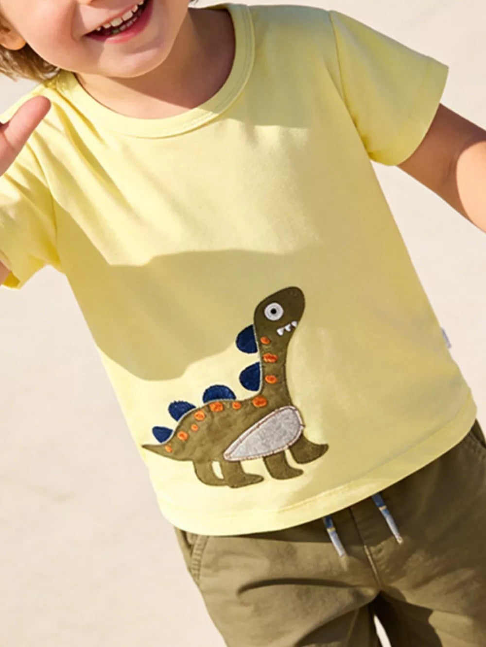 Yellow cotton t-shirt with a green dinosaur appliqué and blue accents.