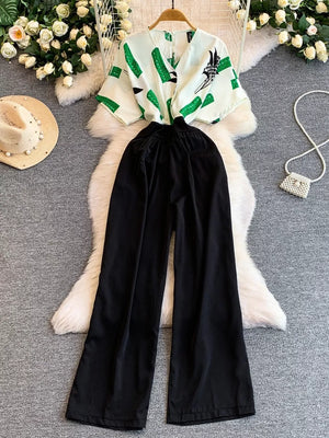 Black wide-leg romper with abstract green print top and pockets.