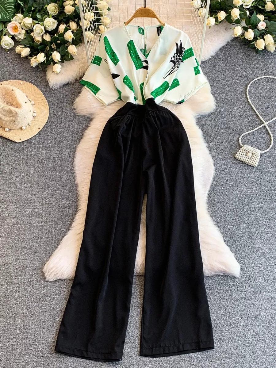 Black wide-leg romper with abstract green print top and pockets.