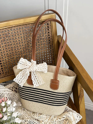 Charming straw shoulder bag with black stripes and lace bow detail