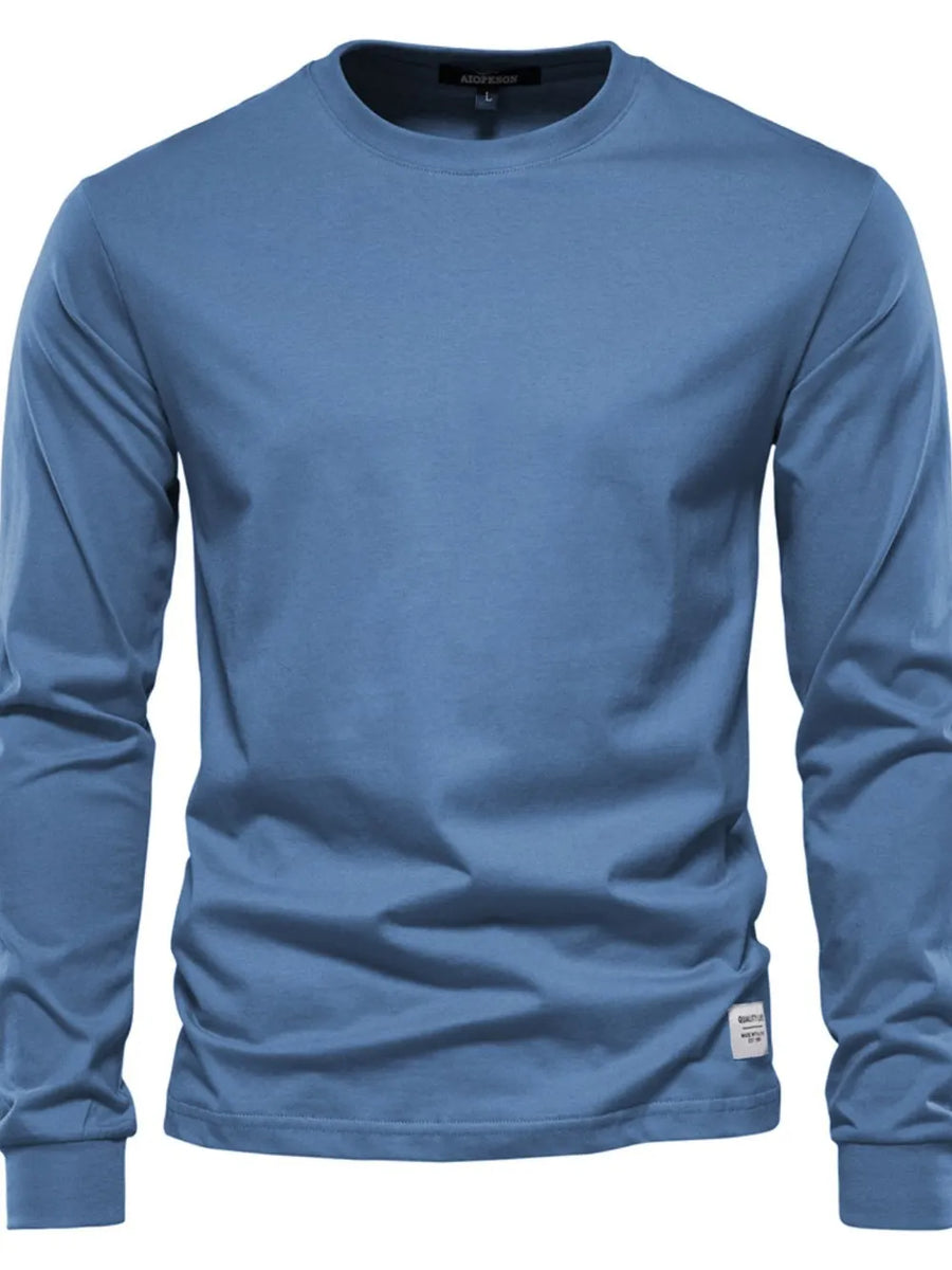 Essential crewneck long sleeve t-shirt in blue with a small logo tag detail.