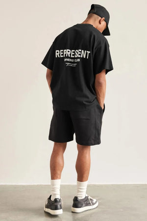 Black oversized graphic tee with white "REPRESENT OWNERS' CLUB" text on back.