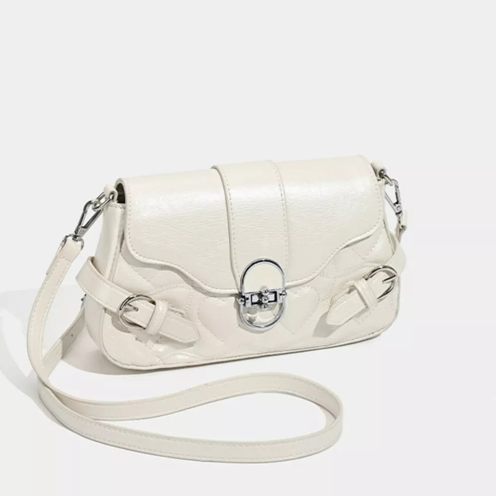 White heart-quilted crossbody bag with buckle accent and silver hardware.